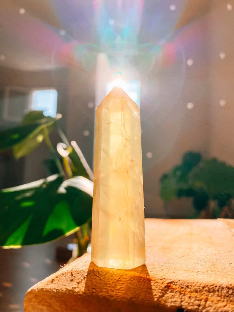 A yellow quartz crystal on a table with a sun shining through it
